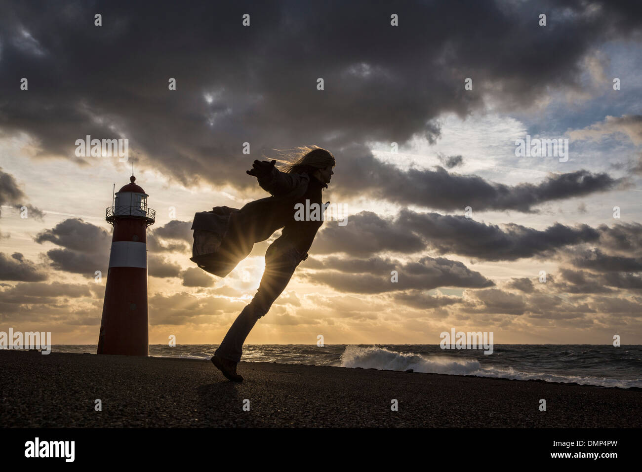 Niederlande, Westkapelle, Leuchtturm am Deich. Frau spielt mit dem Wind bei schweren Sturm Stockfoto