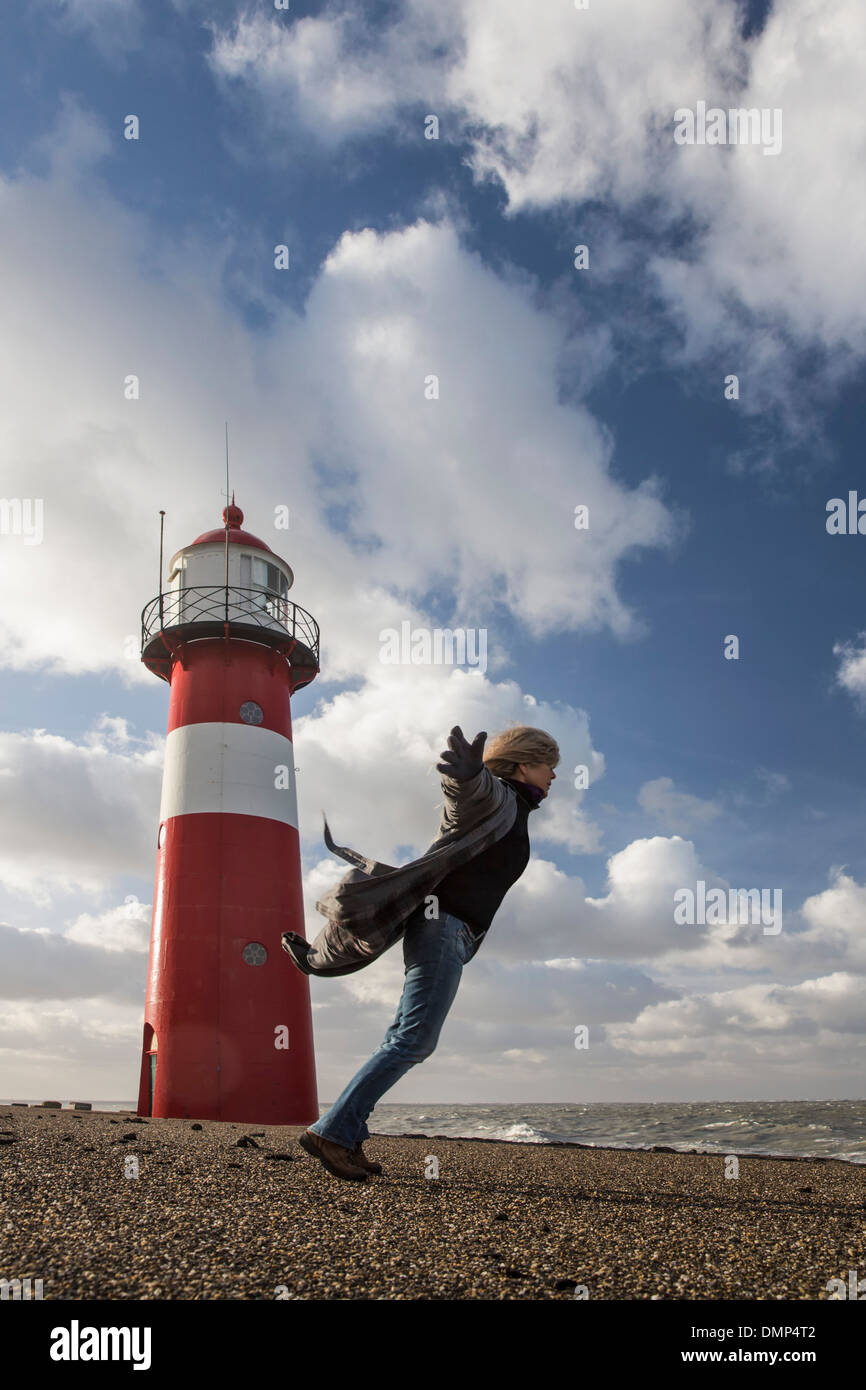 Niederlande, Westkapelle, Leuchtturm am Deich. Frau spielt mit dem Wind bei schweren Sturm Stockfoto