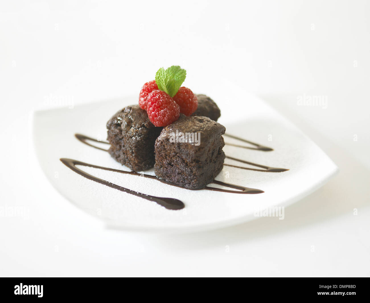 Schokoladen-Brownie Soße Himbeeren Blätter Streusel Abstauben von Puderzucker Zucker Minze Stockfoto