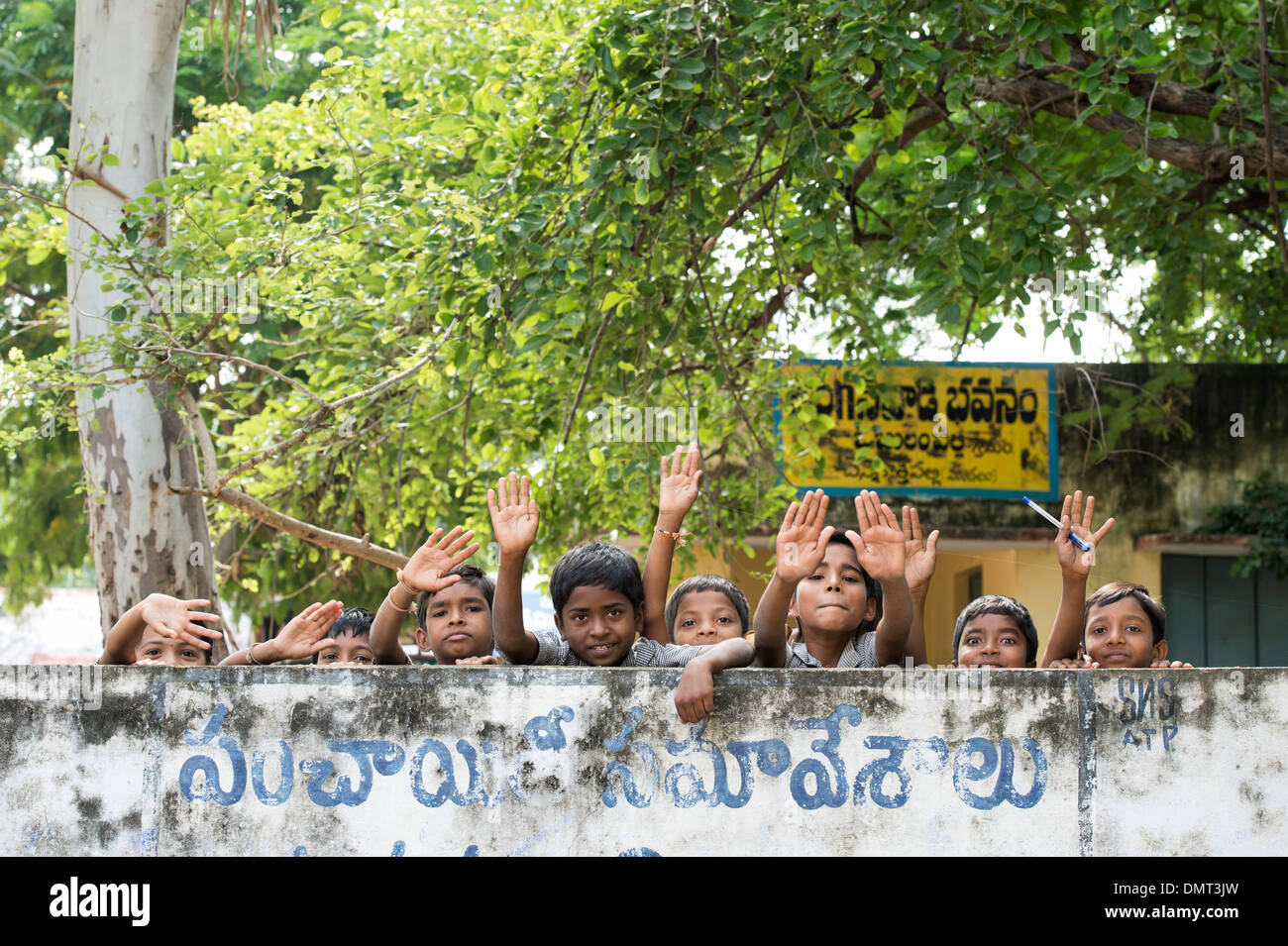 Indische Bauerndorf Schulkinder winken hinter einer Wand. Andhra Pradesh, Indien Stockfoto