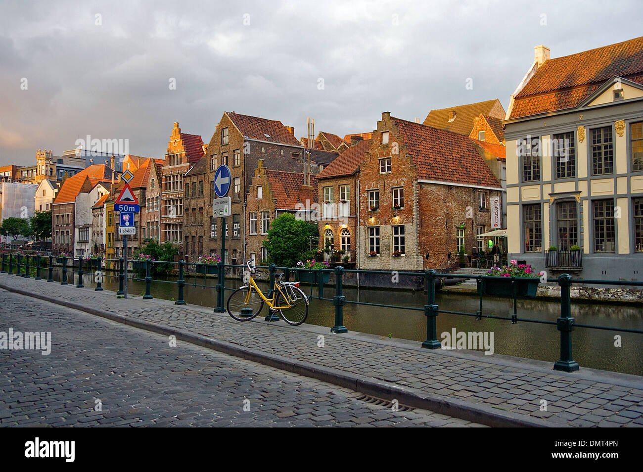 Ein Fahrrad abgestellt auf einem Bürgersteig gepflastert Stein durch das Wasser und die historische Architektur von Gent, Belgien Stockfoto