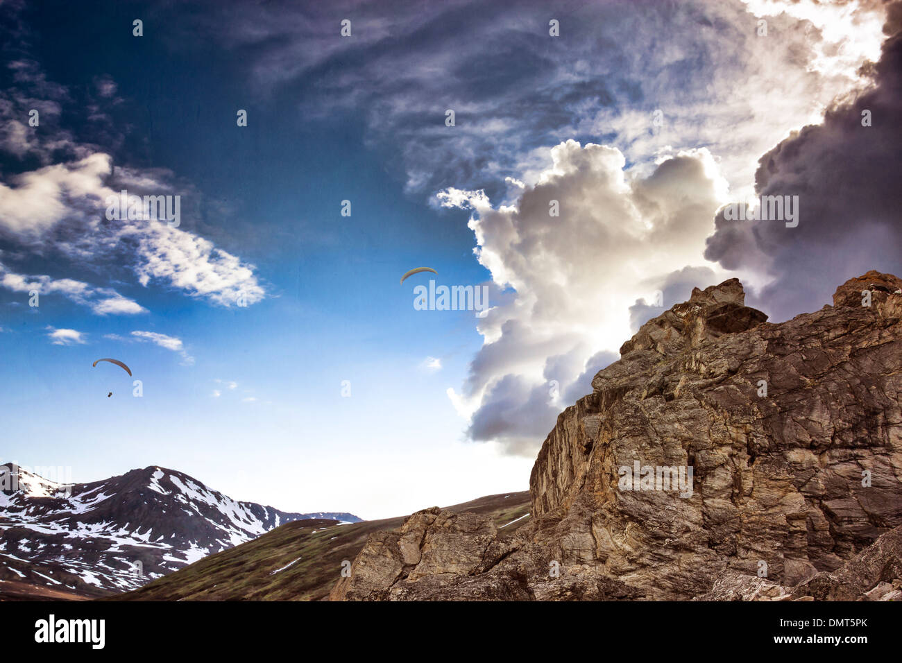 Hängegleiter Segelfliegen in dramatische Wolken über Berggipfel mit Texturen hinzugefügt für einen Fantasy-Look. Stockfoto