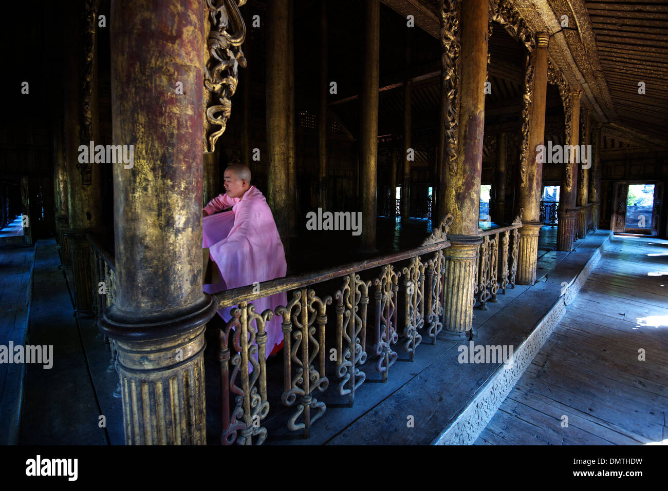 Eine Nonne ordnet ihre Gewänder nach einem Gebet an Shwenandaw Kyaung (Teak-Kloster), Mandalay, Birma. Stockfoto