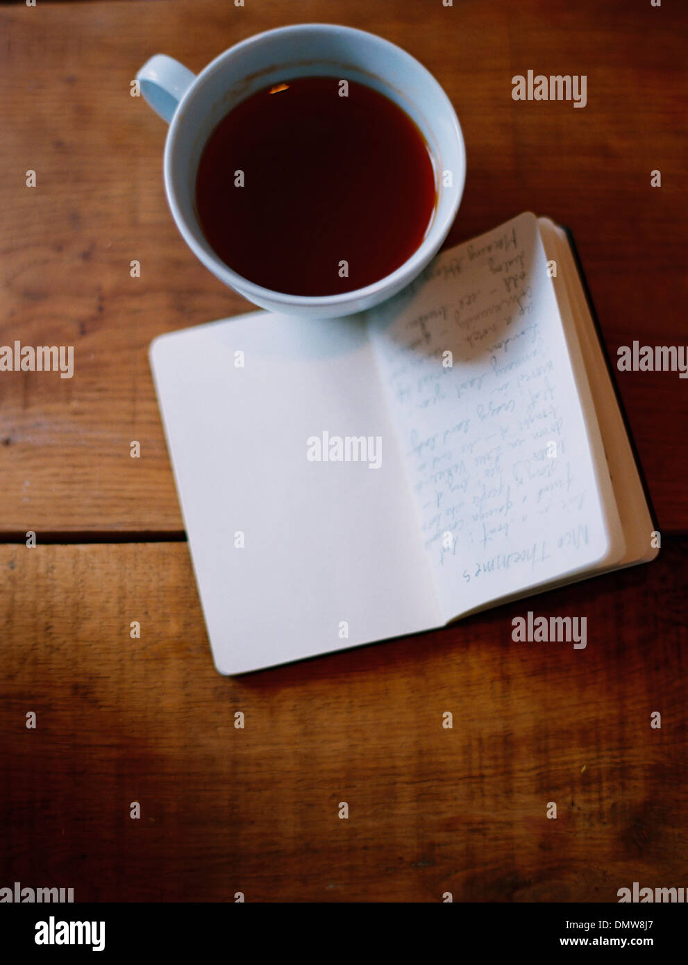Eine kalte Tasse Kaffee und eine handschriftliche Zeitschrift. Stockfoto
