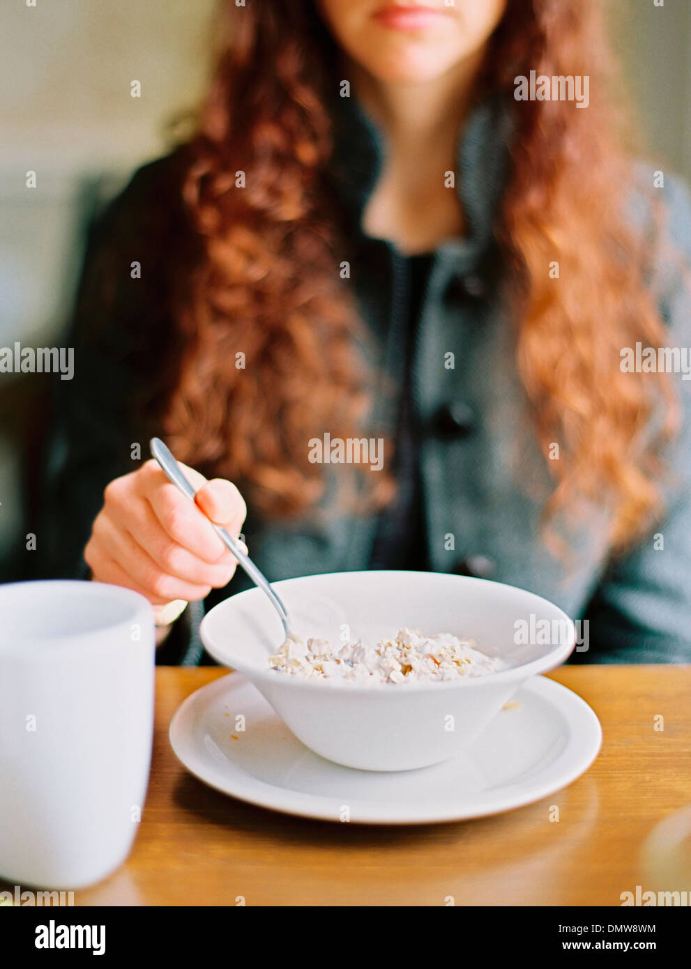 Eine Frau, Frühstücks-Cerealien aus einer weißen Schüssel essen. Stockfoto