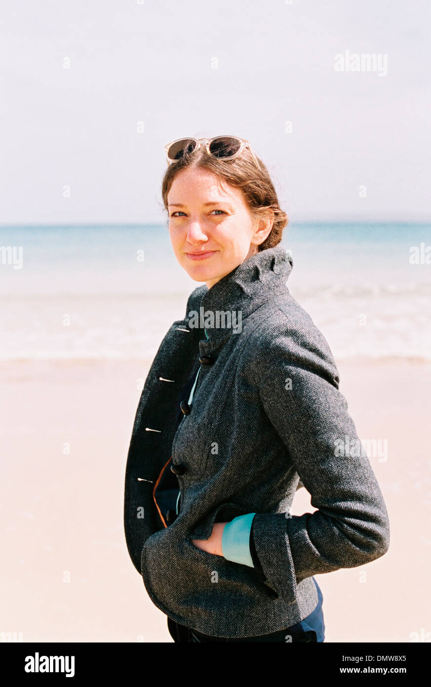 Eine Frau in einem grauen Mantel am Strand. Stockfoto