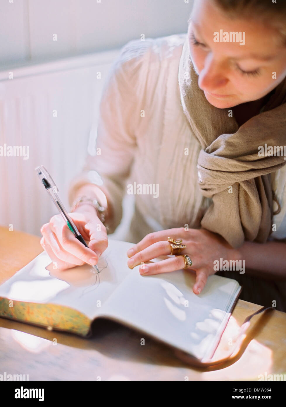 Eine Frau mit einem farbigen Stift zeichnen auf einer leeren Seite eines Tagebuchs. Stockfoto