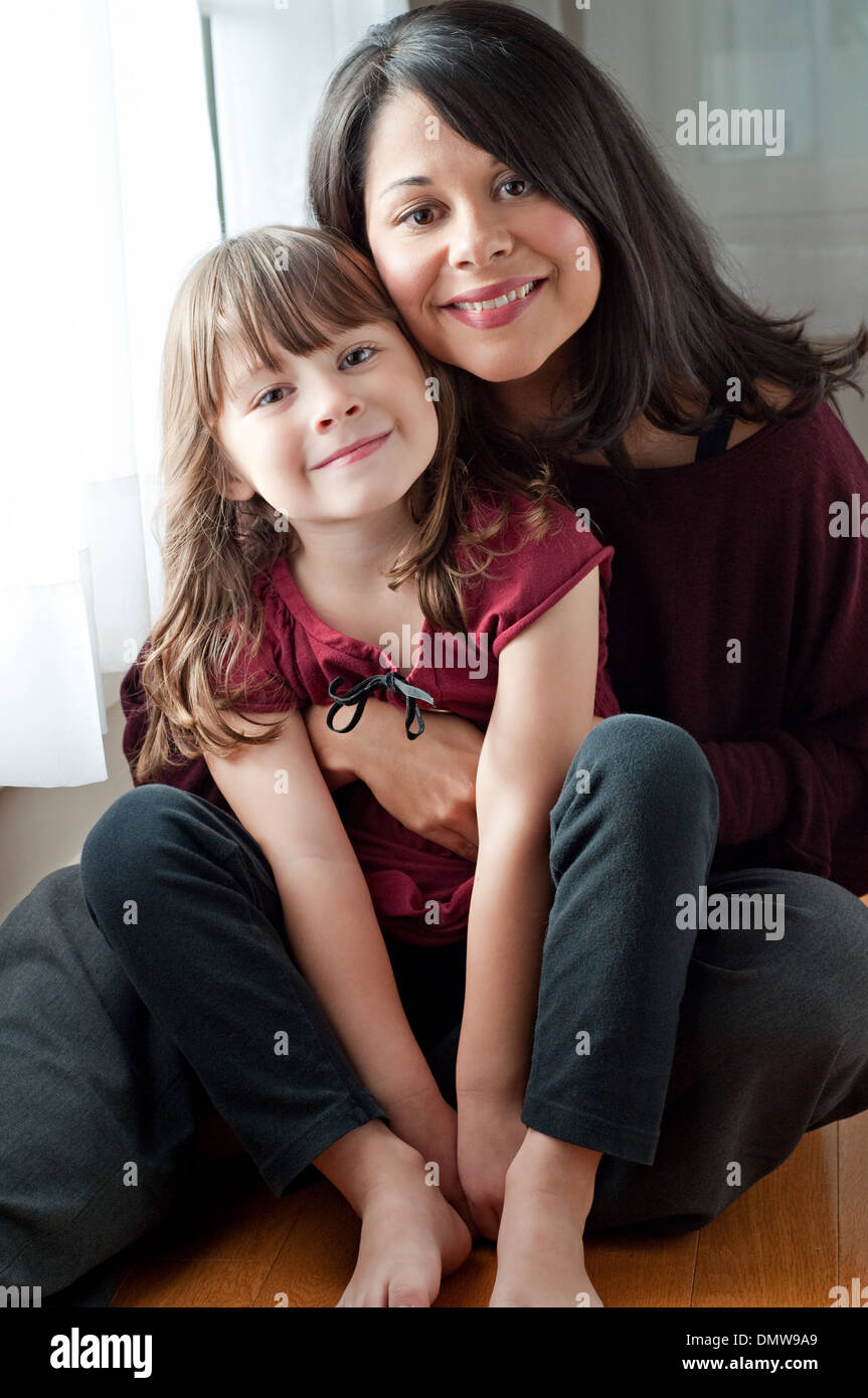 Eine schöne Hispanic Frau hält ihre schöne Tochter, lächelnd. Eine multirassische Mutter und Tochter Familienporträt. Stockfoto