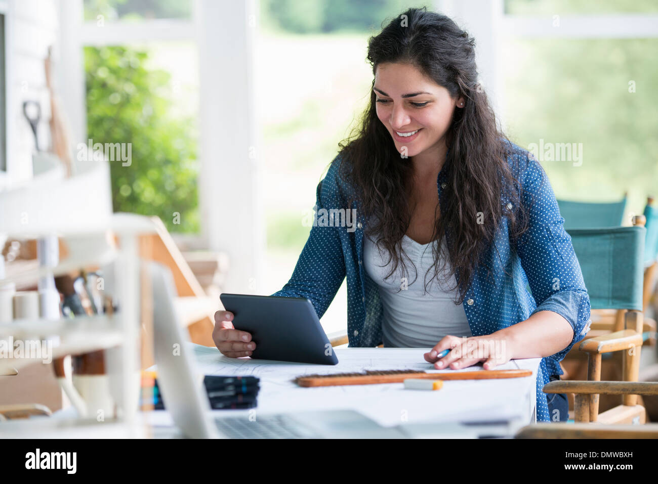 Eine Frau an einem Tisch mit einem digitalen Tablet arbeiten. Stockfoto