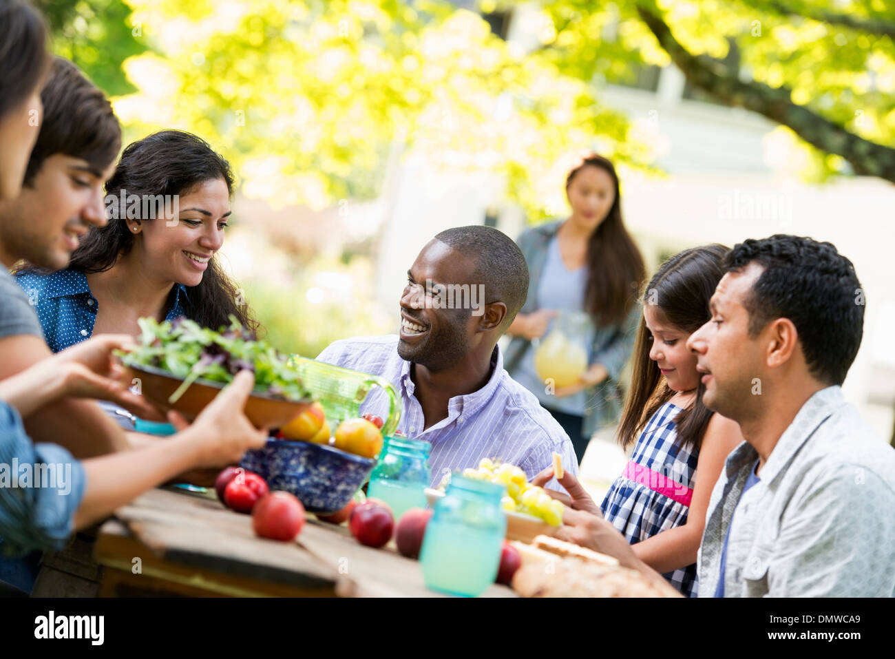 Erwachsene und Kinder an einem Tisch im Garten. Stockfoto