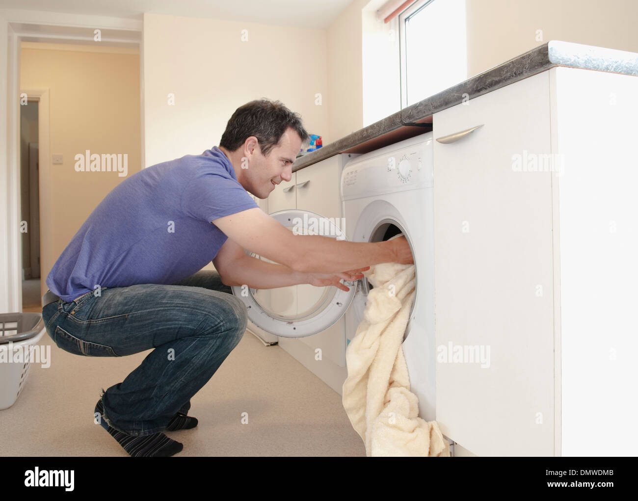Ein Mann, Wäsche in die Waschmaschine. Stockfoto