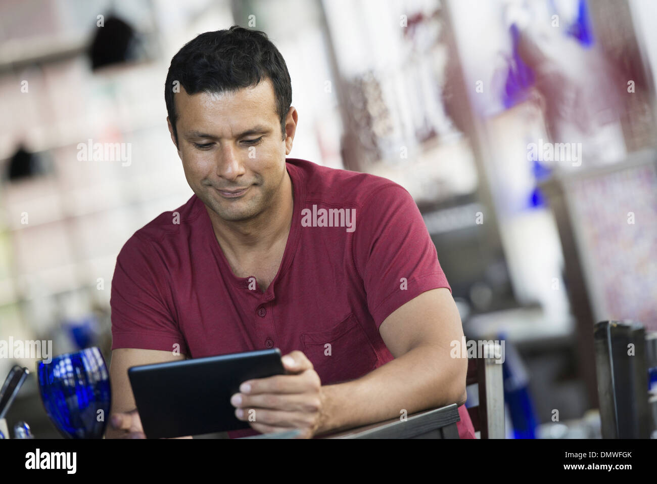 Ein Café-Interieur. Ein Mann sitzt mit einem digitalen Tablet. Stockfoto