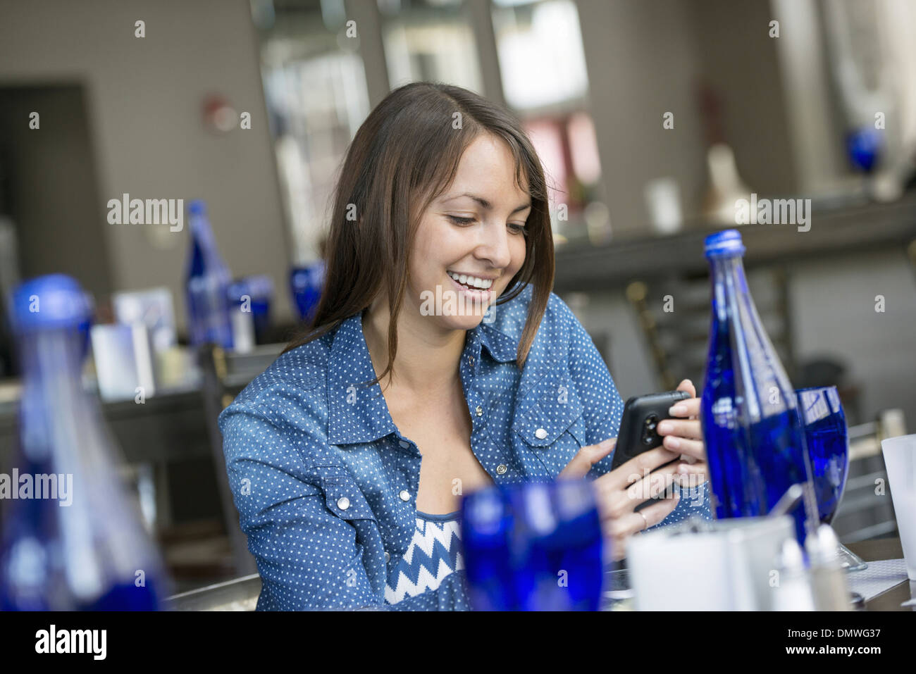 Eine Frau sitzt in einem Café mit einem Smartphone. Stockfoto