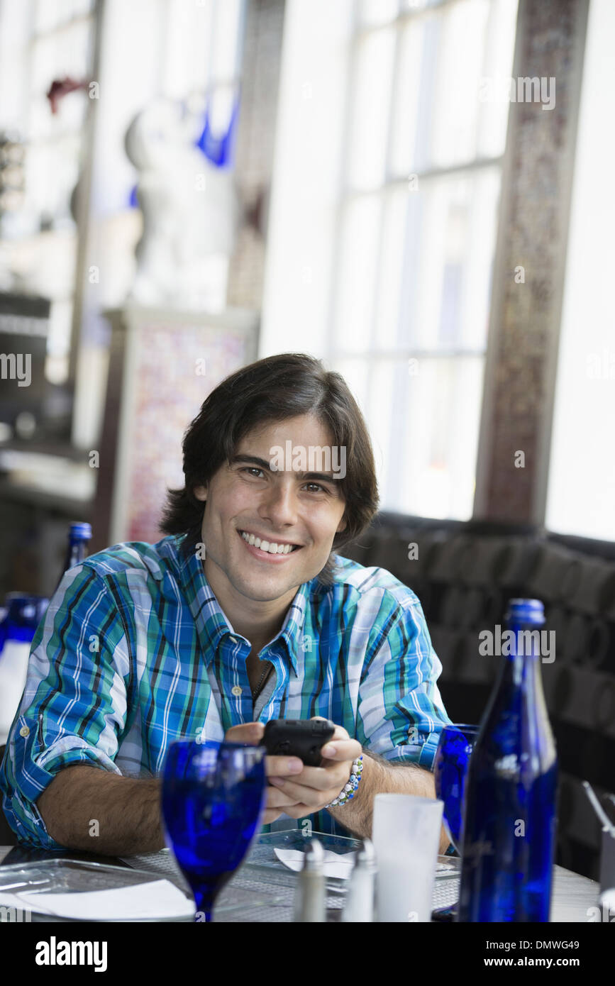 Ein Mann sitzt in einem Café mit einem Smartphone. Stockfoto