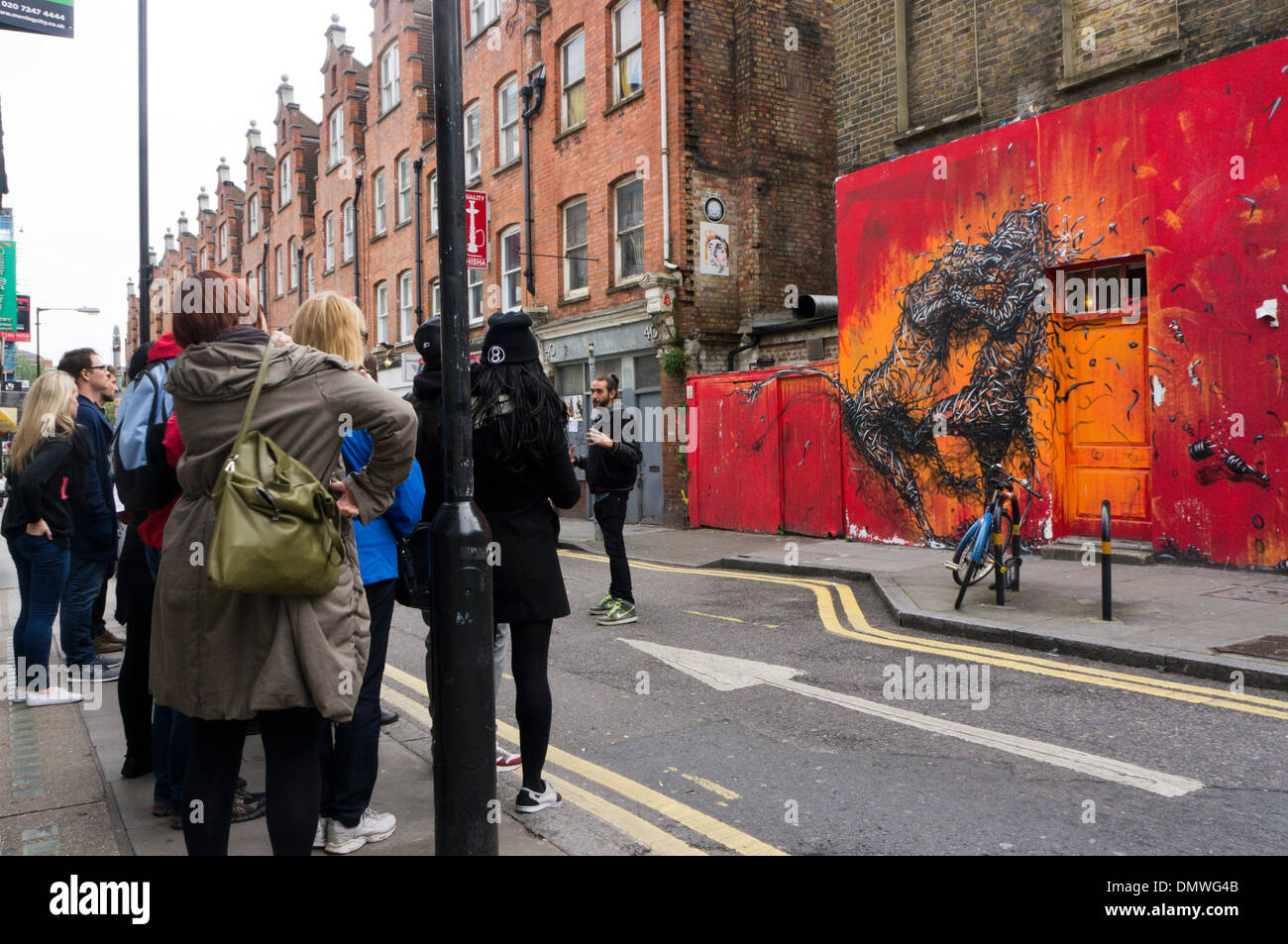 Ein Graffiti-Tour vor eine große Graffiti von zwei Kämpfe Großkatzen von DALeast in der Hanbury Street, in der Nähe von Brick Lane, Whitechapel Stockfoto
