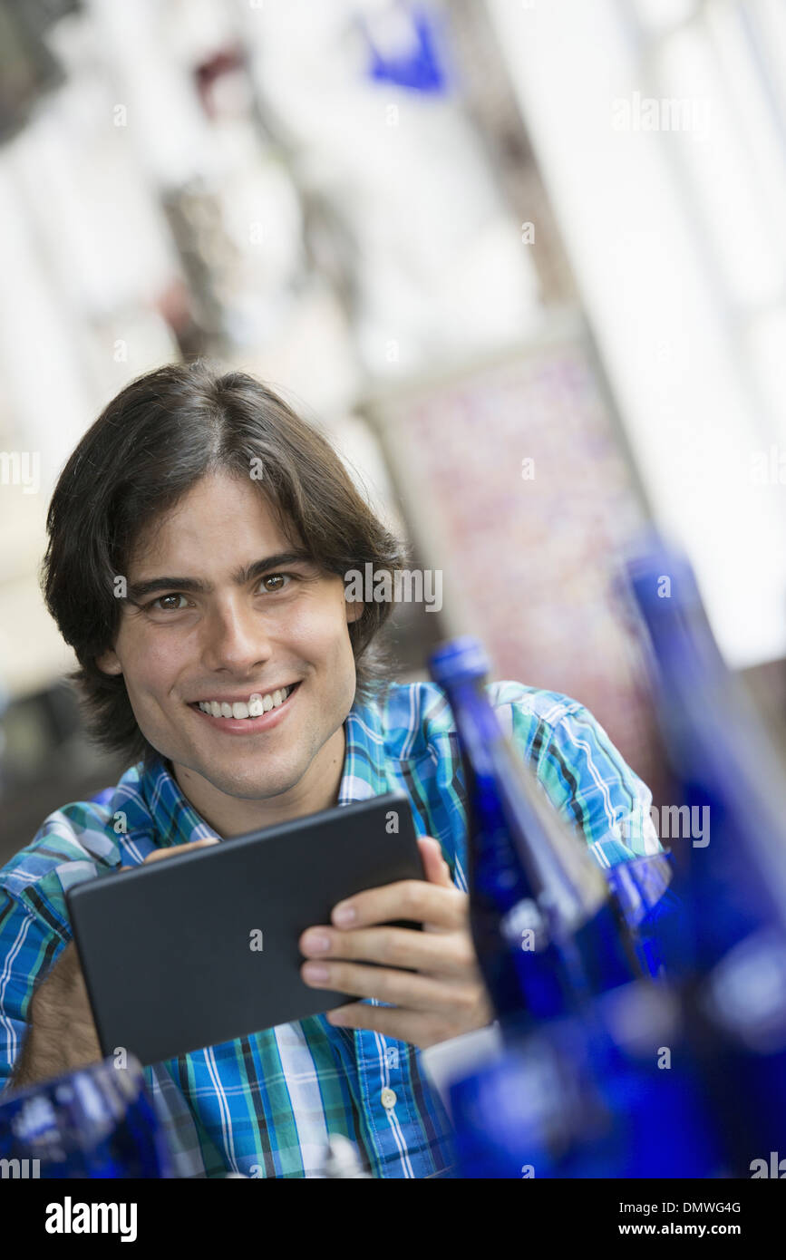 Ein Café-Interieur. Ein Mann sitzt mit einem digitalen Tablet. Stockfoto