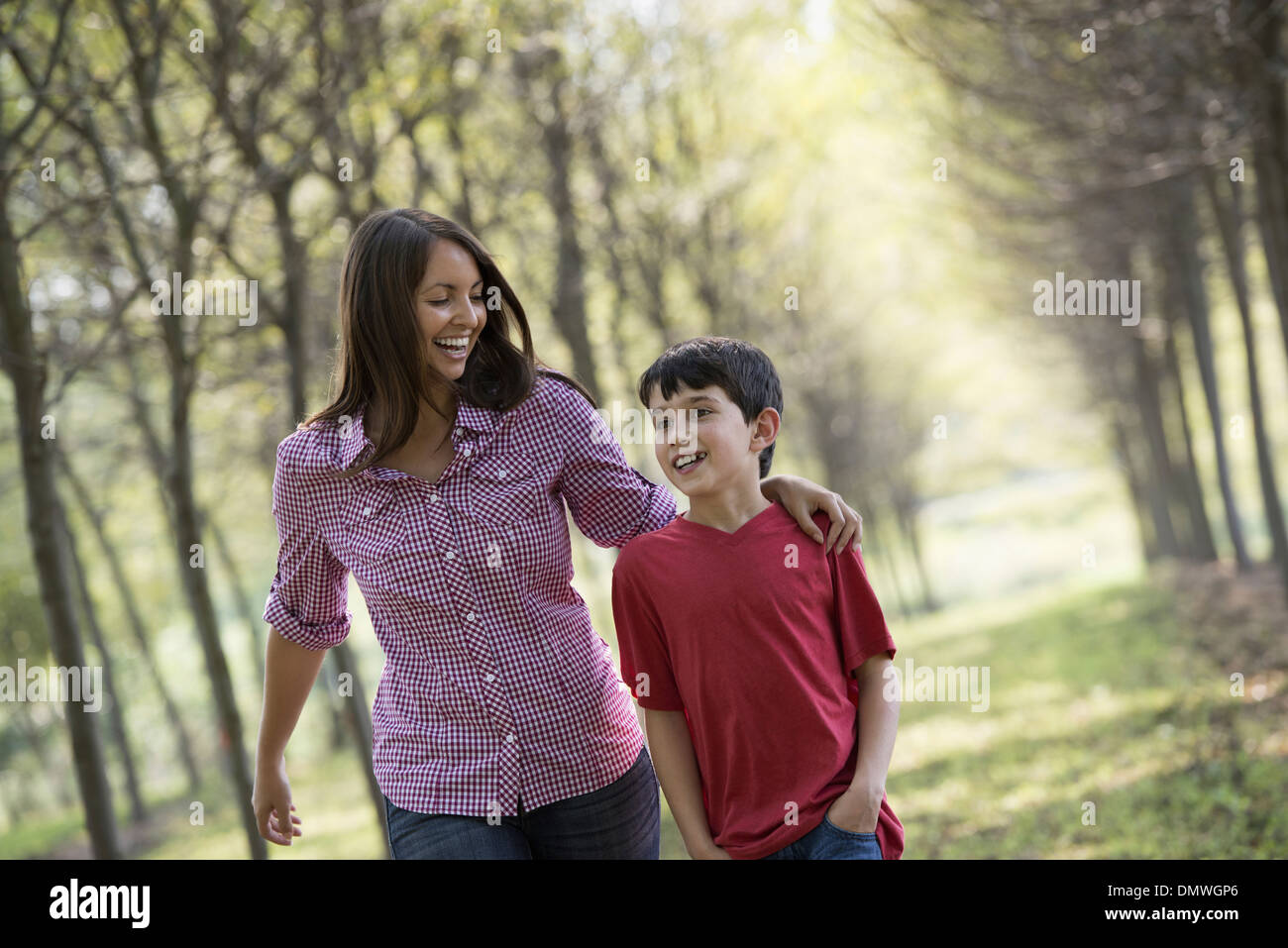 Eine Frau und ein Kind zu Fuß hinunter eine Allee von Bäumen. Stockfoto