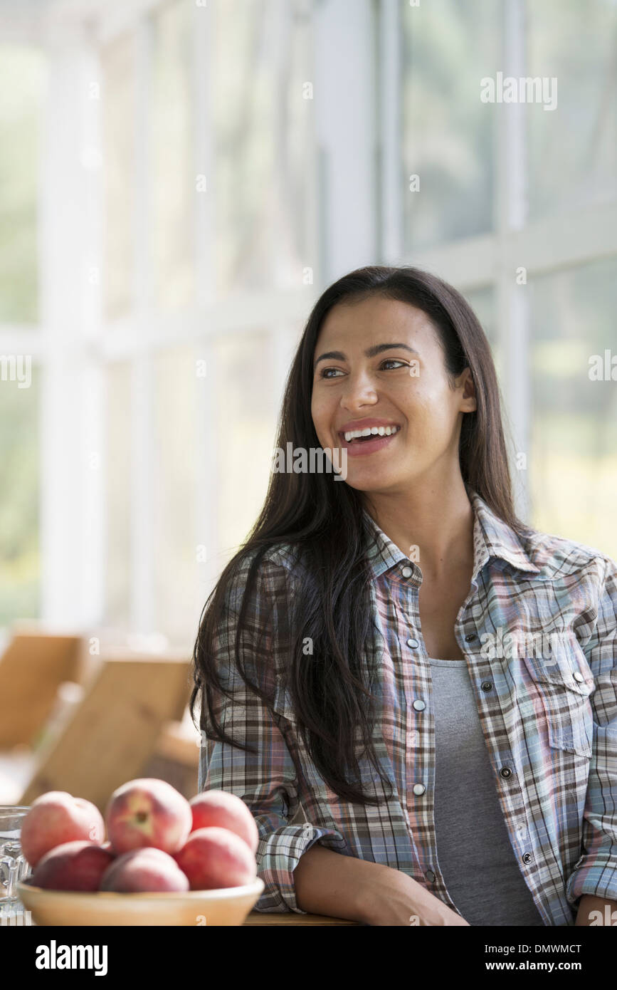 Eine glückliche junge Frau sitzt an einem Tisch. Stockfoto