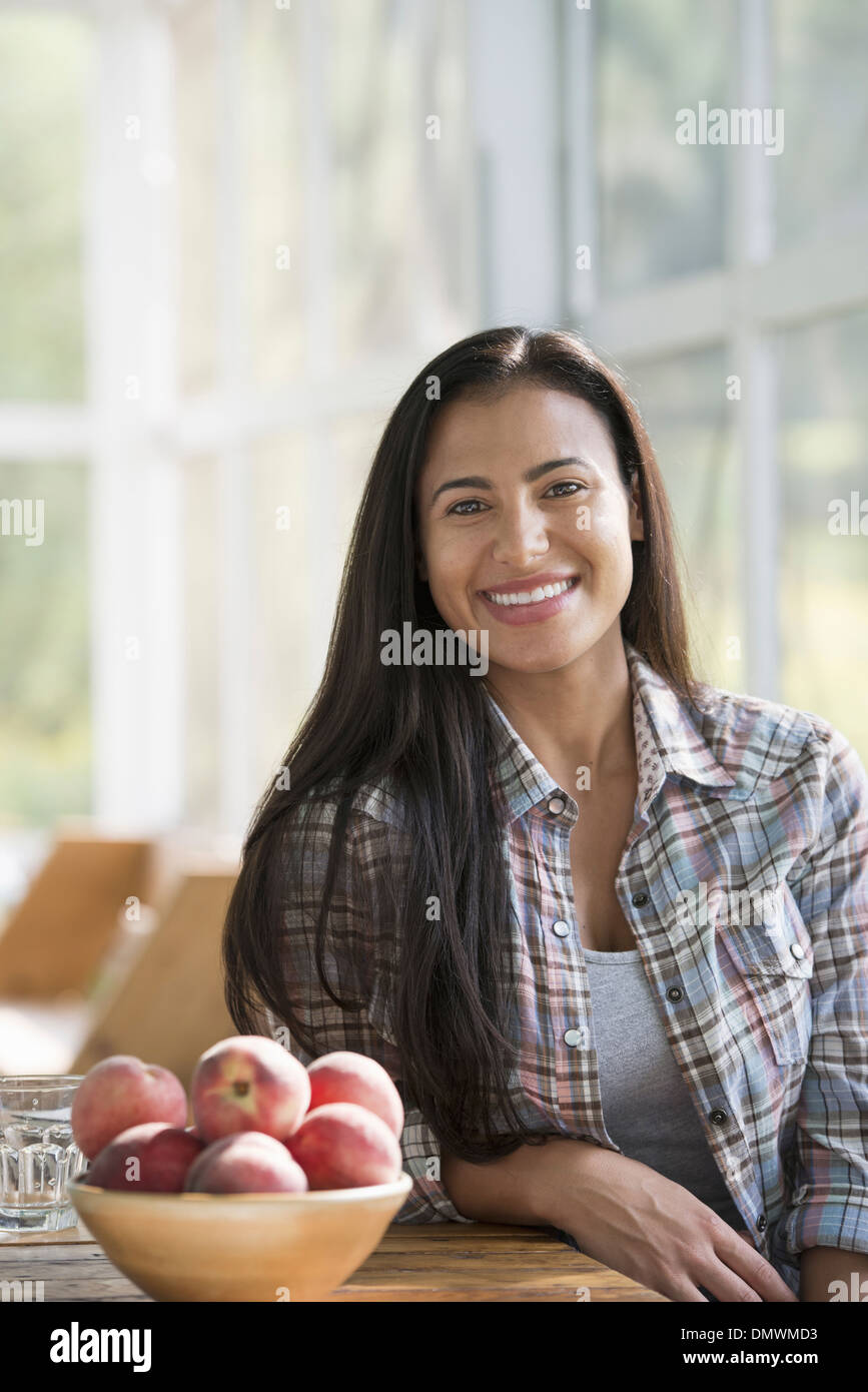Eine glückliche junge Frau sitzt an einem Tisch. Stockfoto
