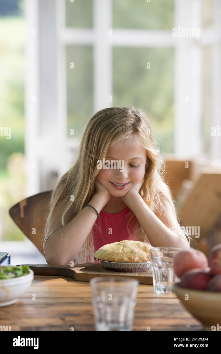 Ein junges Mädchen, ein Gebäck Kuchen lächelnd zu betrachten. Stockfoto