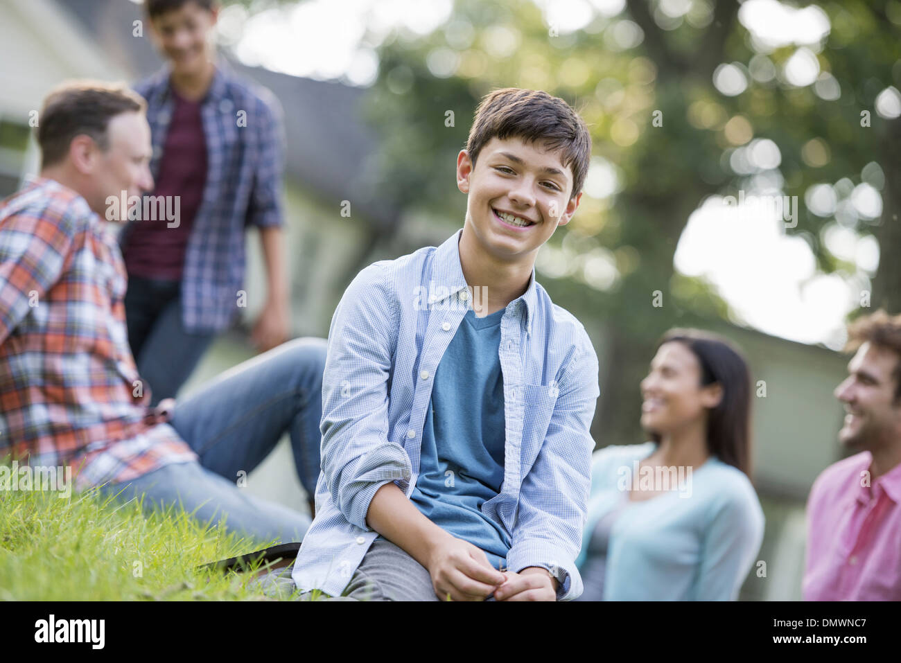 Ein Junge sitzt auf dem Rasen auf einem Sommerfest. Stockfoto