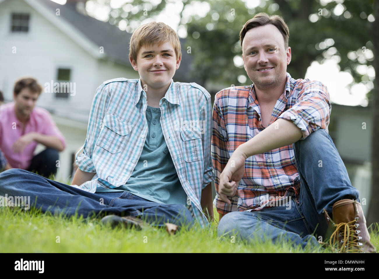 Vater und Sohn auf einer Sommerparty auf dem Rasen sitzen. Stockfoto