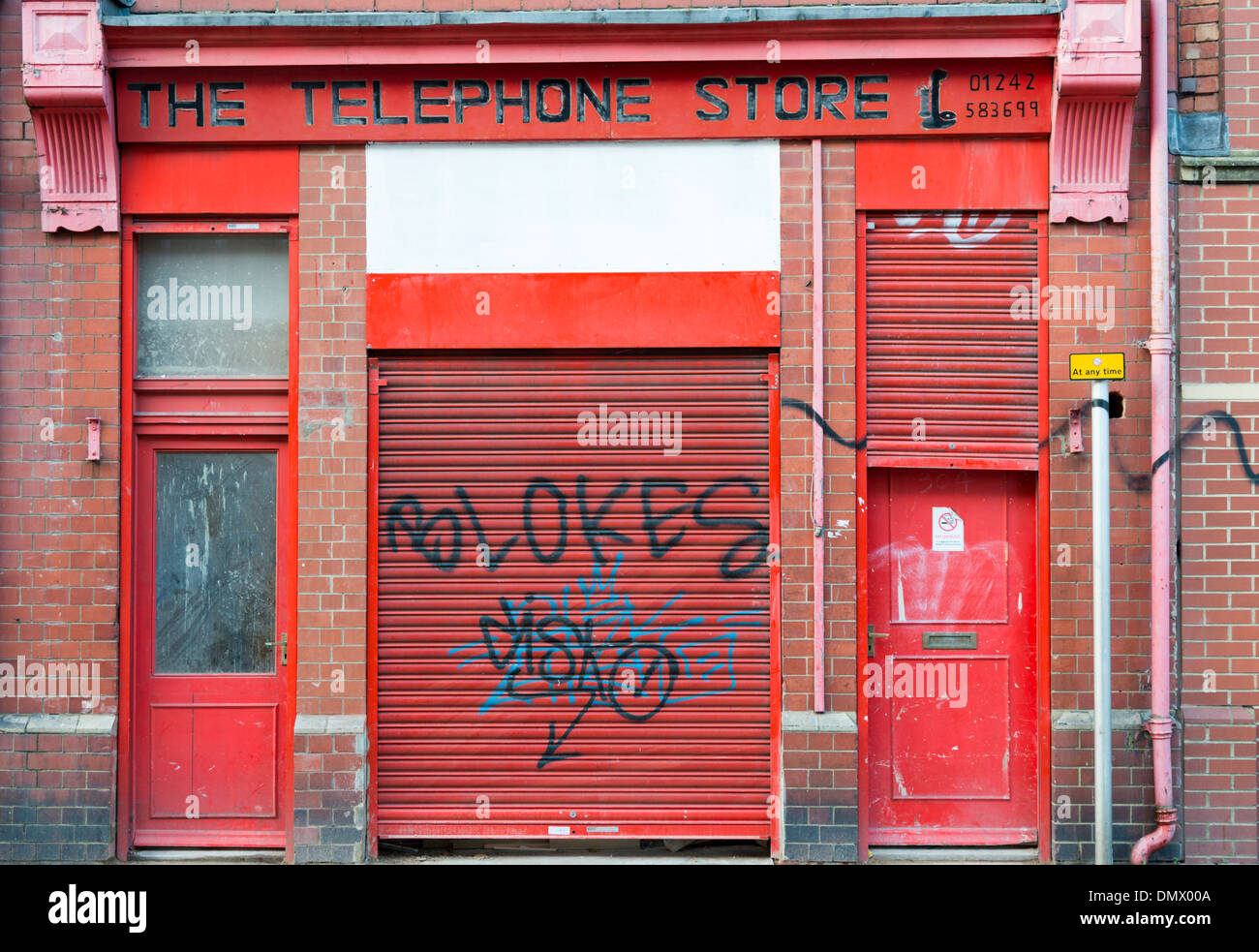 Ein heruntergekommenes Telefon shop in Cheltenjam UK mit roten Türen und Graffiti auf sie. Stockfoto