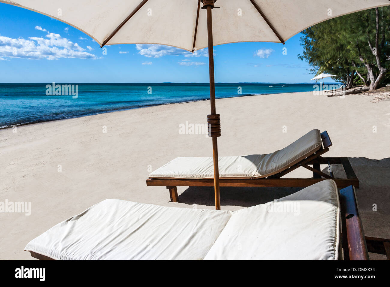 Liege und Sonnenschirm an einem wunderschönen tropischen Strand Stockfoto