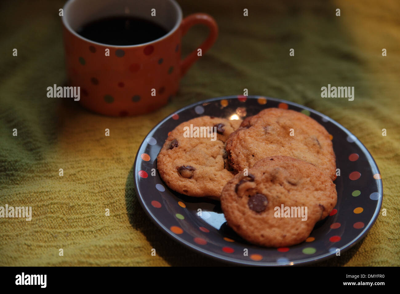 Eine Tasse schwarzen Kaffee mit drei Schokoladenkekse auf einem Polka-Dot-Teller Stockfoto