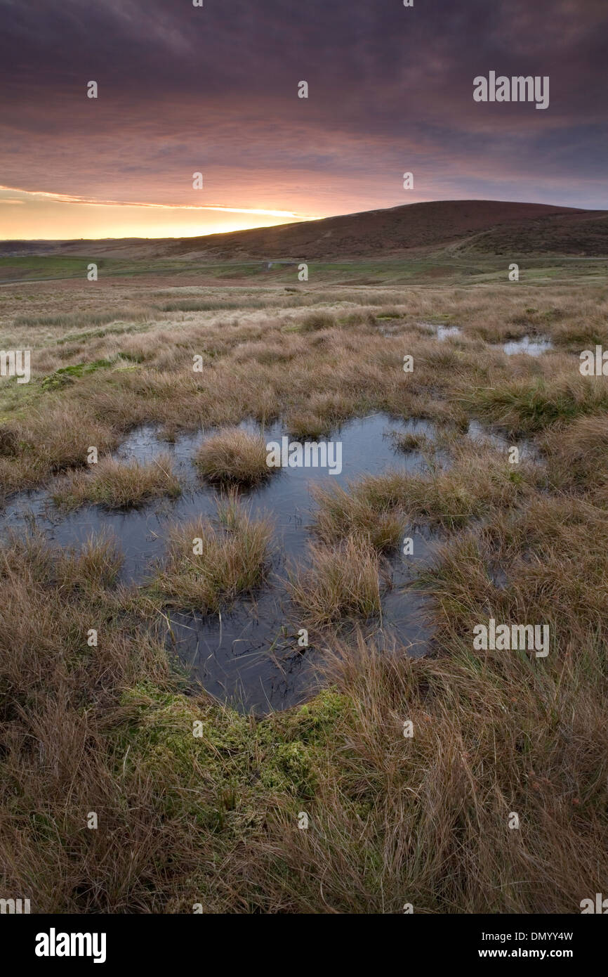 Dieses Foto zeigt einen der vielen Pools im Goyts Moos. Die Sonne geht über der A54 Macclesfield Road, Buxton, Peak District Stockfoto