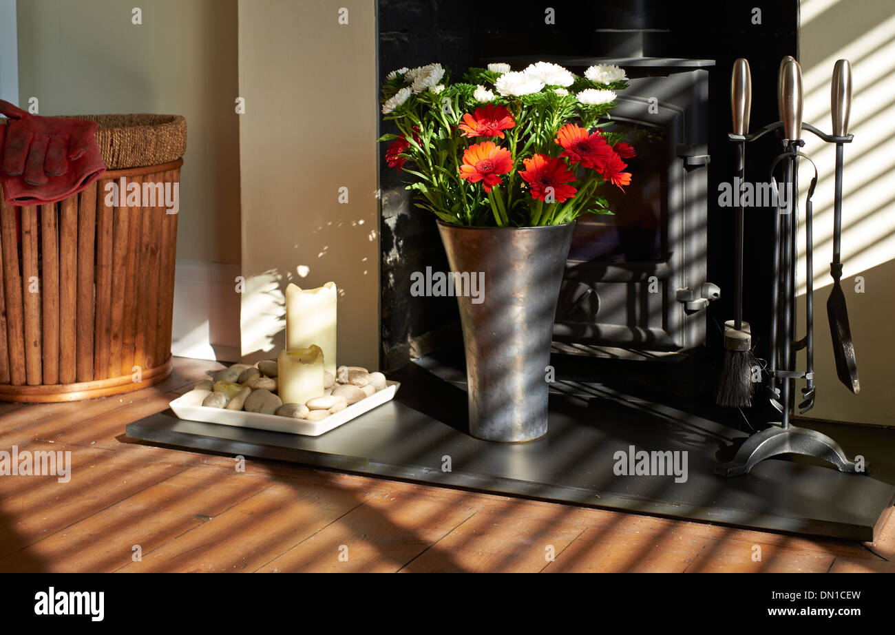 Sonnenschein leuchtenden Blumen auf einer Schiefertafel Herd in einem Wohnzimmer. Stockfoto