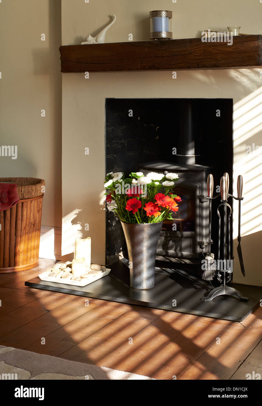Sonnenschein leuchtenden Blumen auf einer Schiefertafel Herd in einem Wohnzimmer. Stockfoto