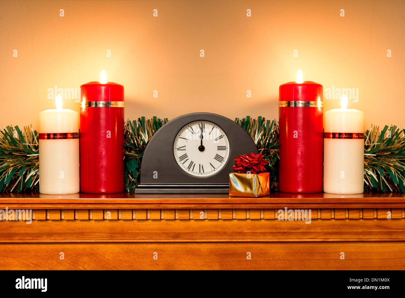 Ein Weihnachten Kaminsims mit einer Uhr Mitternacht und vier Kerzen brennen hell zeigen. Stockfoto