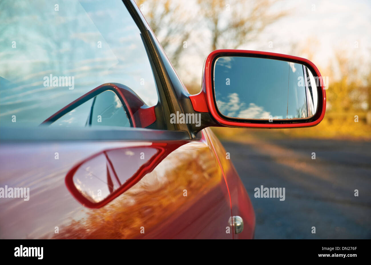 Die Außenspiegel eines roten Autos bei Sonnenuntergang. Stockfoto