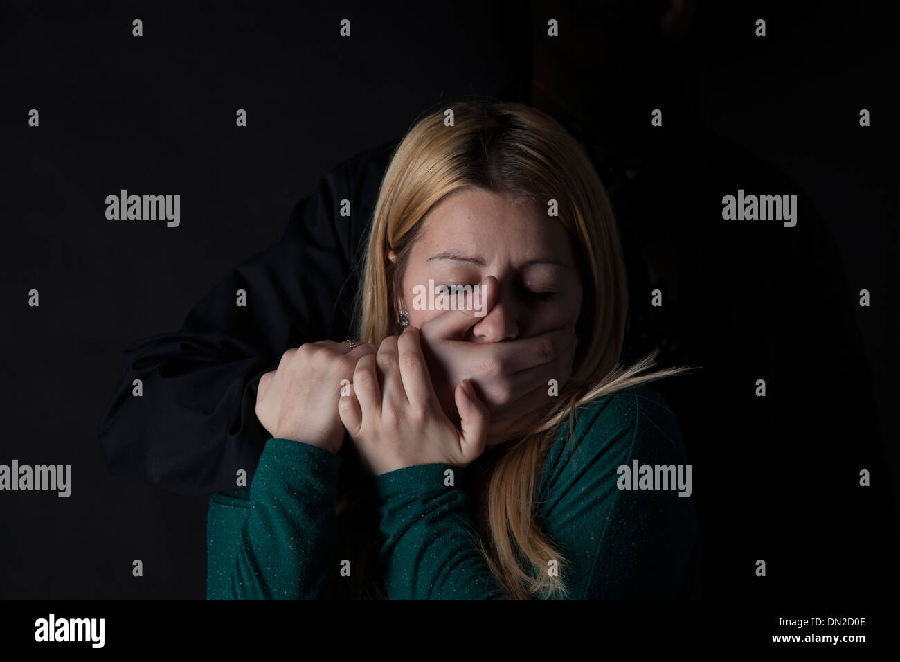 Junge Frau mit der Hand über den Mund von hinten. Stockfoto