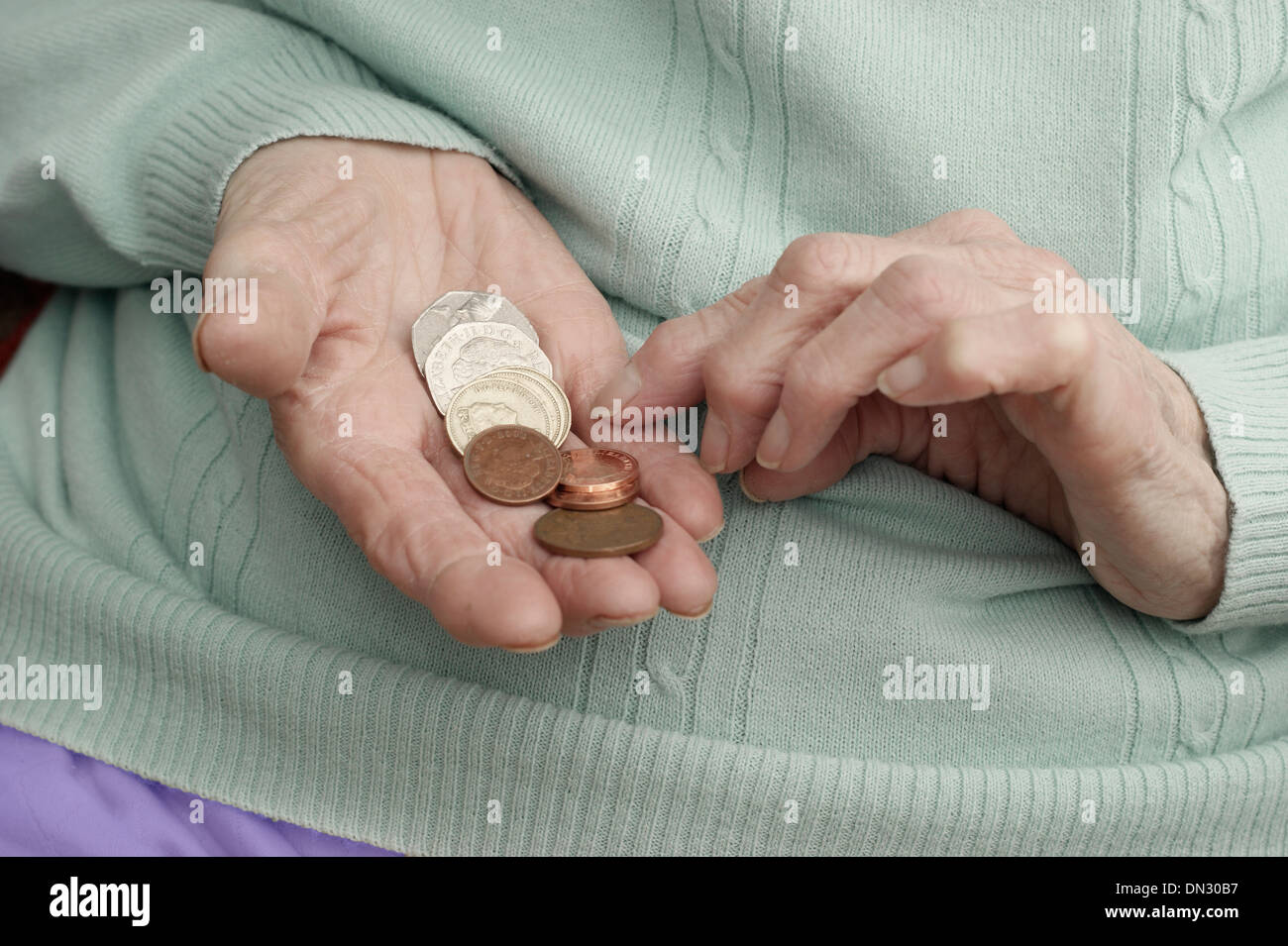 Ältere Frau mit einer Mischung aus Münzen (Umweg über Geld in Zeiten der Sparmaßnahmen) Stockfoto