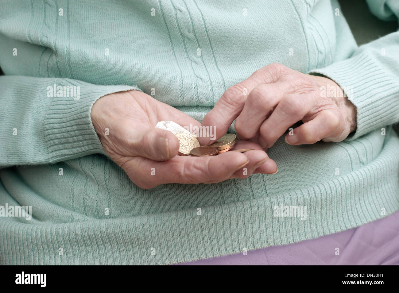 Ältere Frau mit einer Mischung aus Münzen (Umweg über Geld in Zeiten der Sparmaßnahmen) Stockfoto