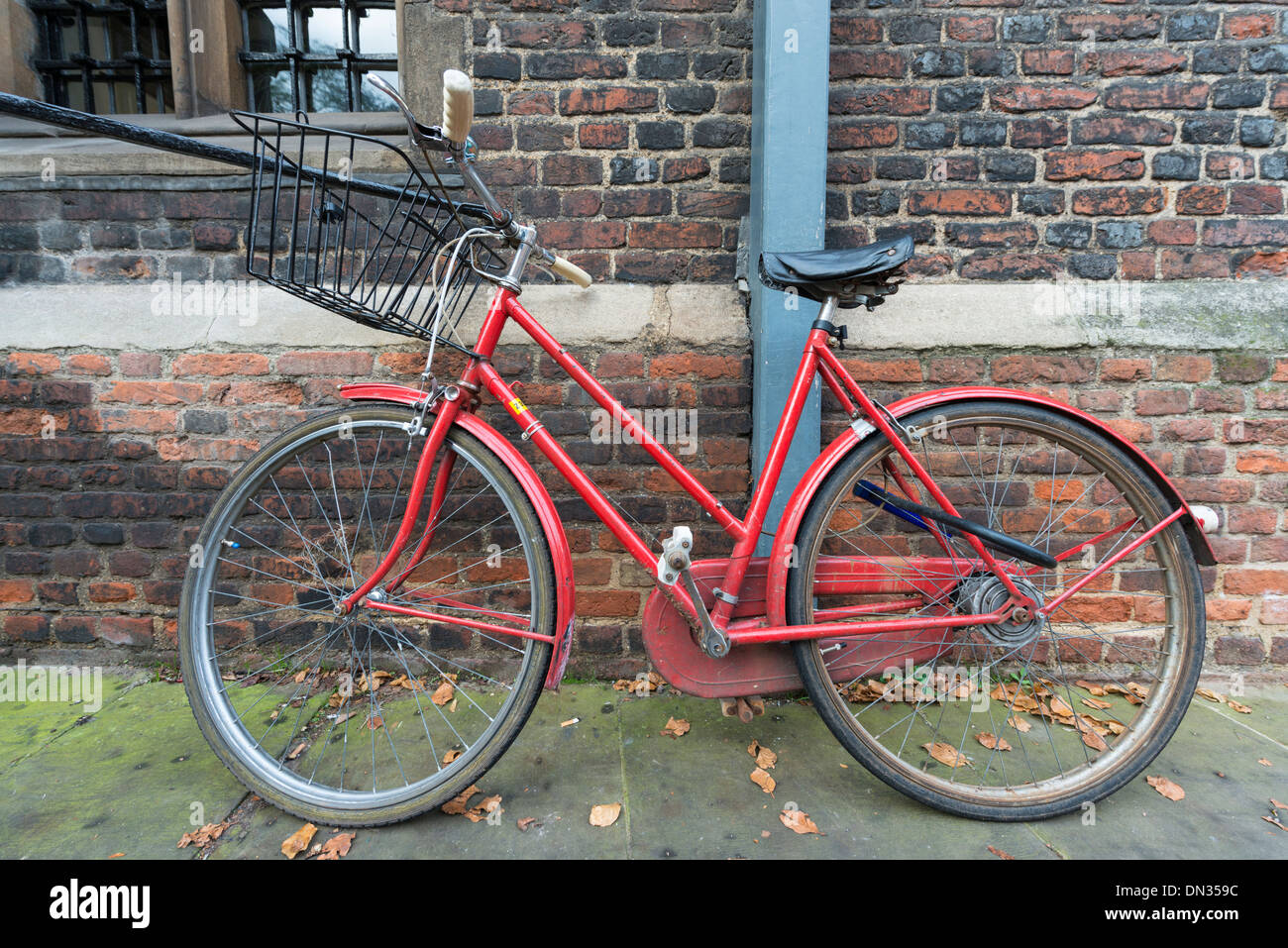 Ein rotes Fahrrad Parken gegen eine Wand in Cambridge UK Stockfoto
