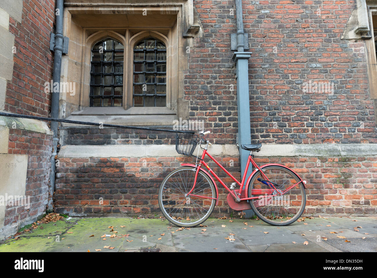 Ein rotes Fahrrad Parken gegen eine Wand in Cambridge UK Stockfoto