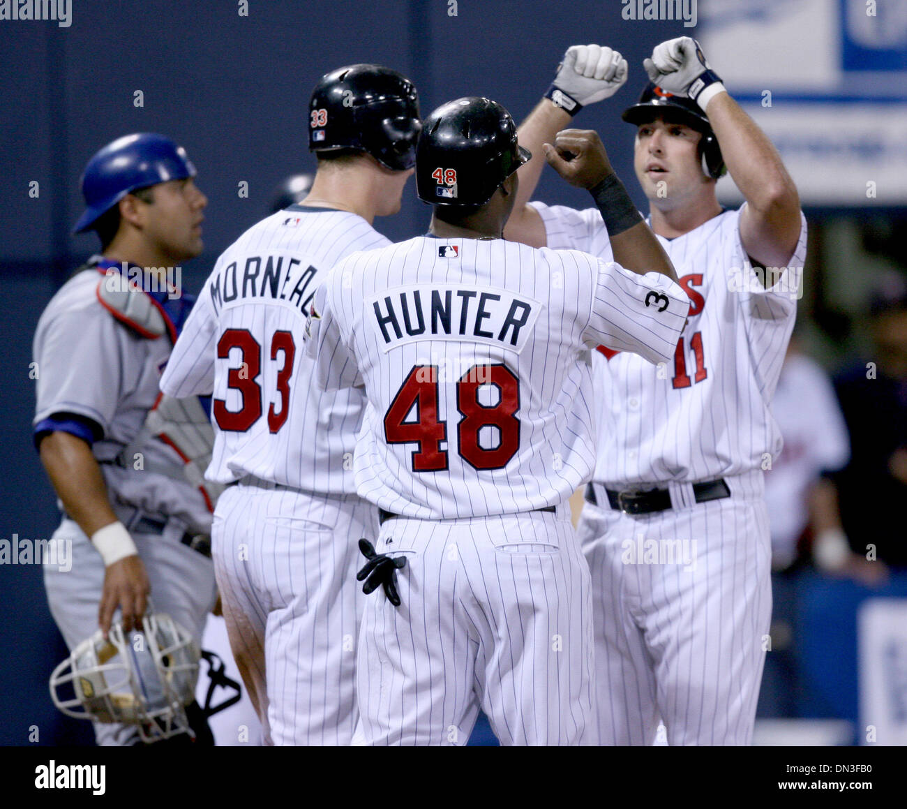 31 Jun 2006; Minneapolis, MN, USA; Minnesota Twins Josh Rabe (rechts) klopfte einen Home Run-off der Texas Rangers' Starter John Rheinecker, Justin Morneau (links) und Torii Jäger (Mitte) zu bringen, die ihn auf den Teller gratuliert. Die Zwillinge besiegten die Rangers 15-2 am Metrodome in Minneapolis, Minnesota, Montag, 31. Juli 2006.  Obligatorische Credit: Foto von Jeff Wheeler/Minneap Stockfoto