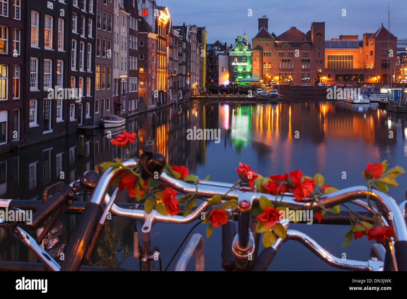 Kanal, Fahrrad und Gebäude bei Nacht. Damrak. Amsterdam, Holland Stockfoto
