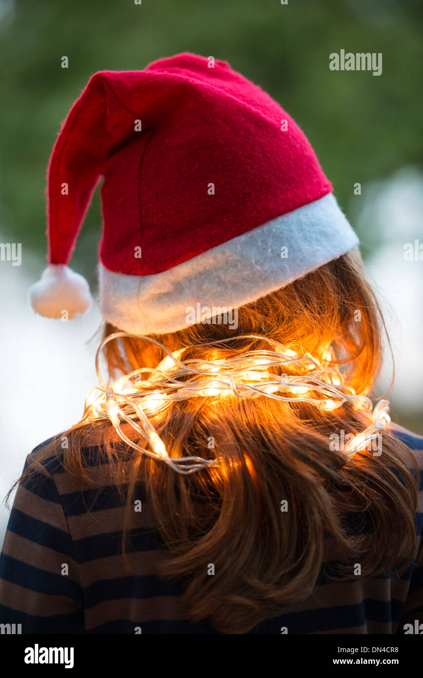 Ein kleines Mädchen gekleidet in einem Santa Hut und Fee Weihnachtsbeleuchtung Stockfoto