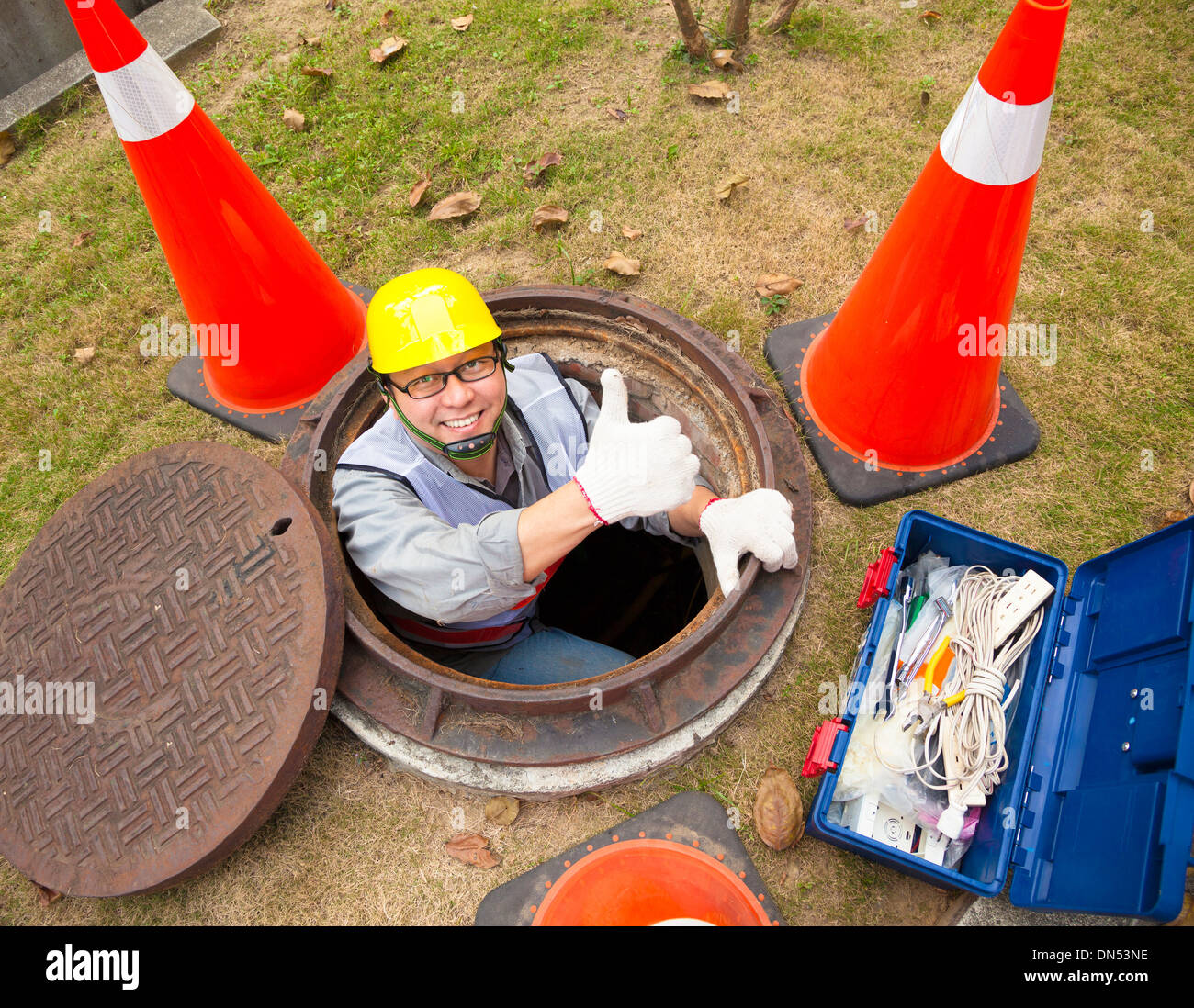 Kanalisation-Arbeiter in den Schacht mit Daumen Stockfoto