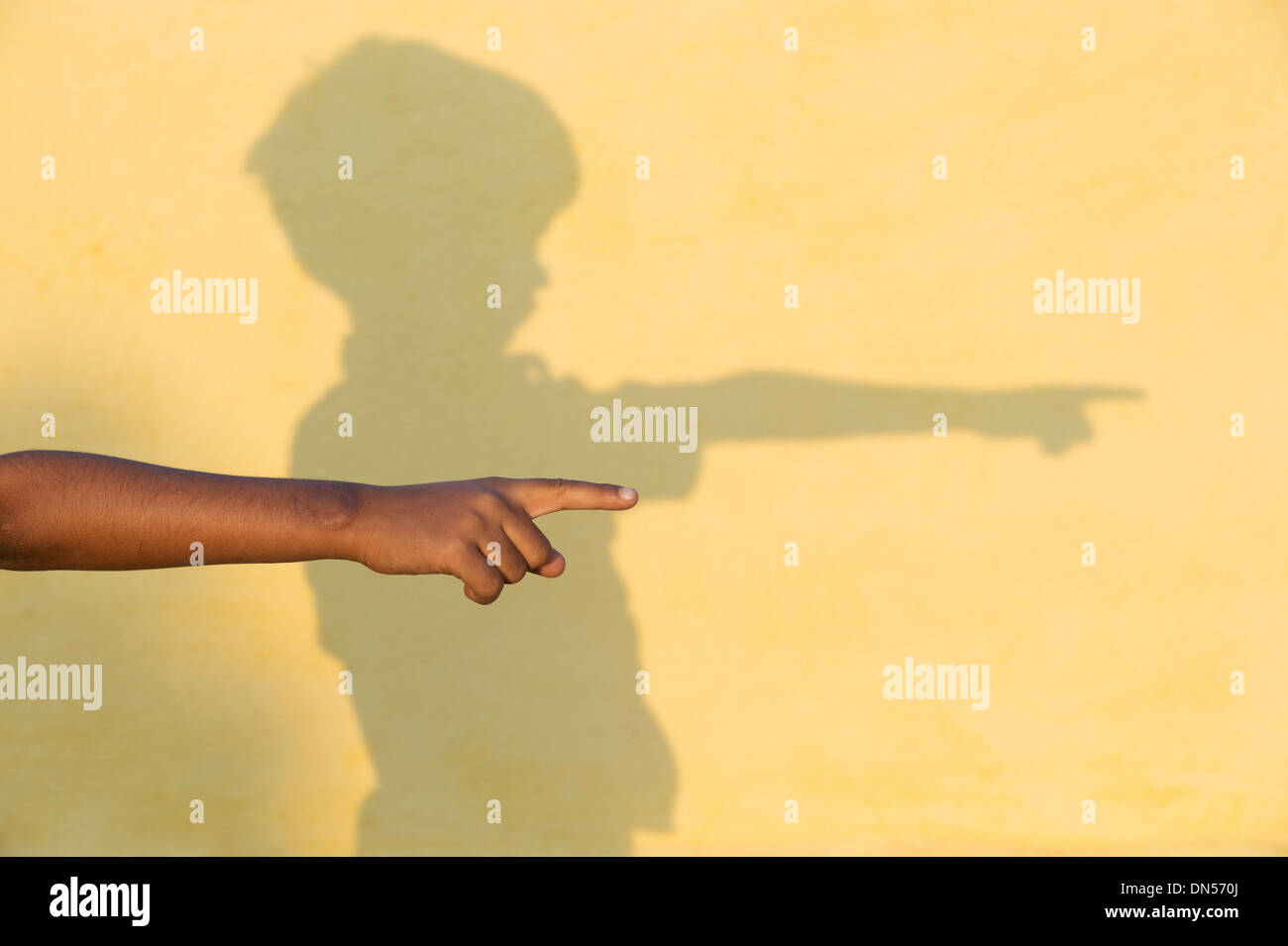 Junge indische Bauerndorf Jungs zeigen Hand mit Schatten an der Wand der Sonne beleuchtet. Andhra Pradesh, Indien Stockfoto
