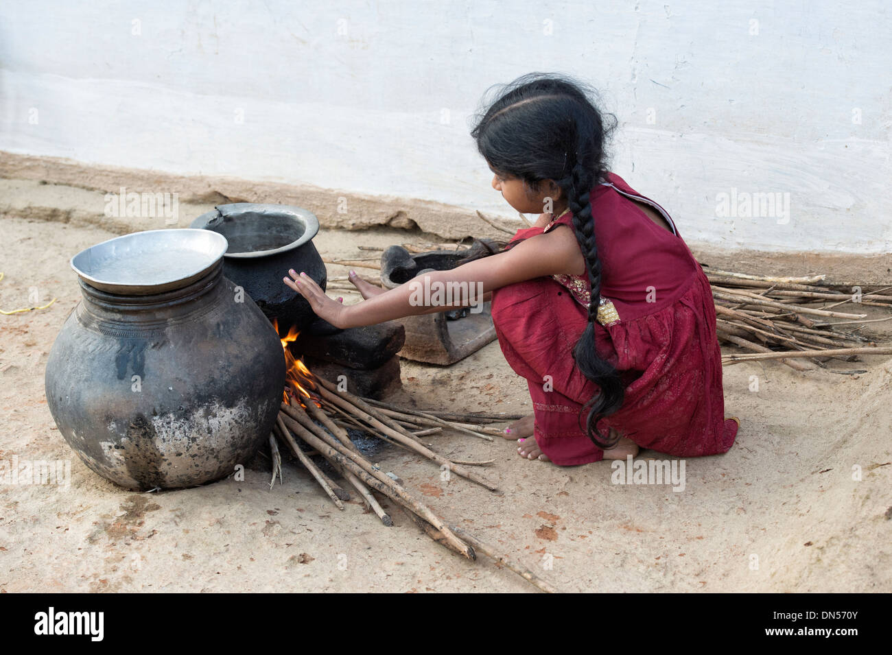Junge Inderin Warmhalten von offenem Feuer in einem indischen Dorf. Andhra Pradesh, Indien Stockfoto
