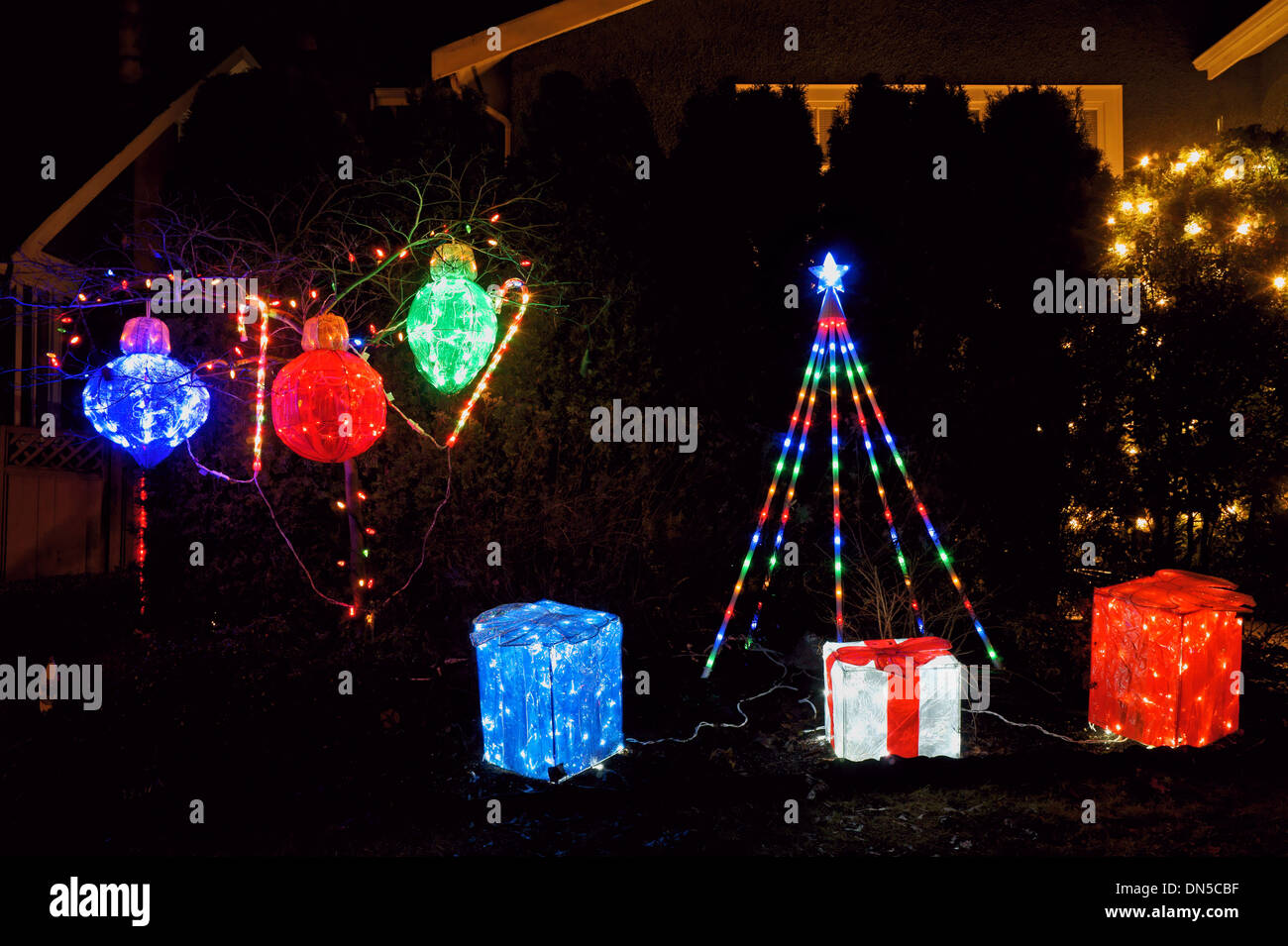 Weihnachten Beleuchtung Display mit verpackte Geschenke und Baumschmuck auf den Vorgarten eines Hauses Stockfoto