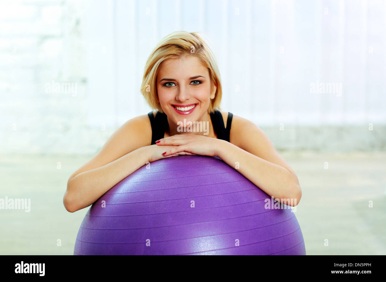 Junge fröhliche Fit Frau stützte sich auf dem fitball Stockfoto