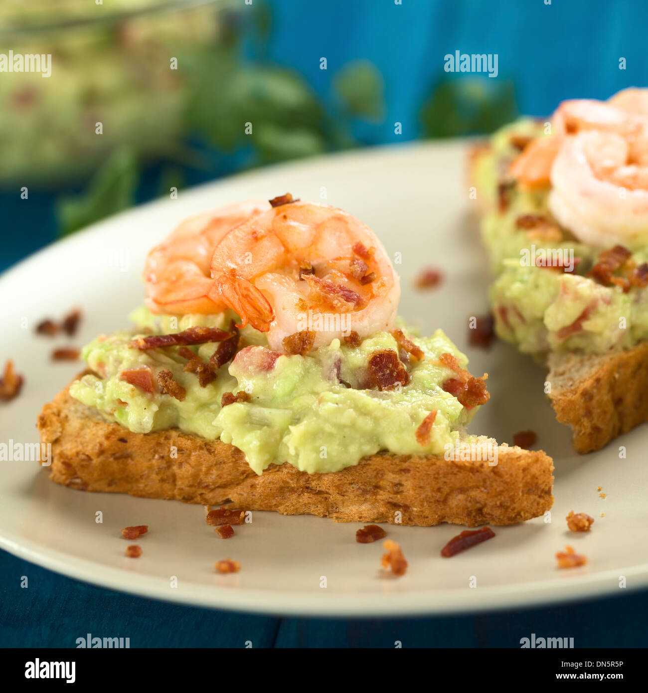 Vollkorn Toast Brotscheiben mit Guacamole, gebratene Garnelen und gebratenen Speckwürfeln Stockfoto