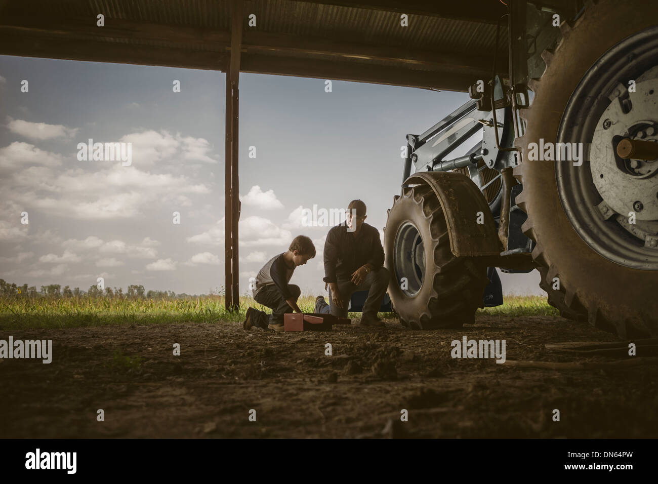 Kaukasische Vater und Sohn arbeiten an Traktor Stockfoto