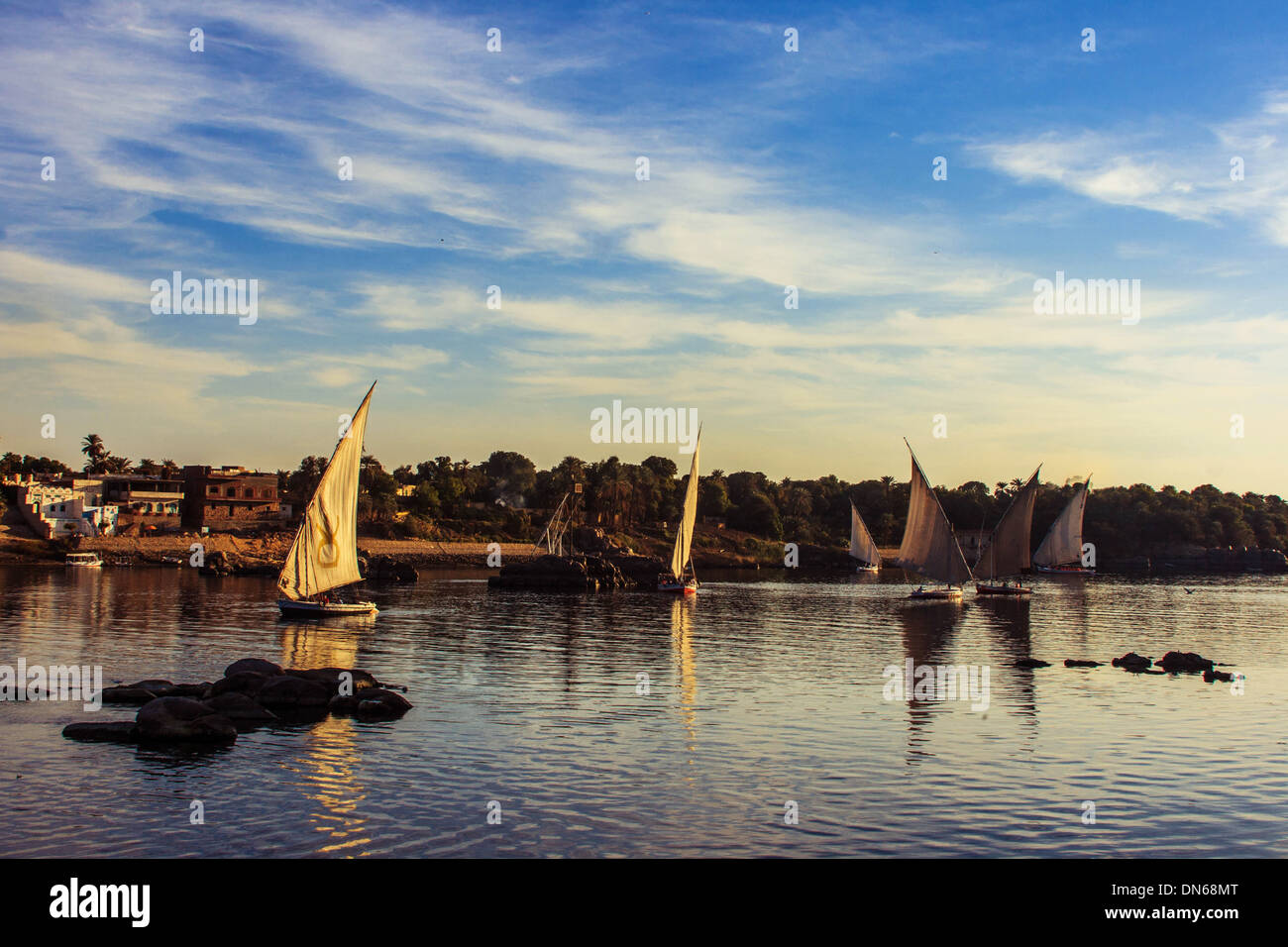 Nil Fluss Assuan Boot Sonnenuntergang Nuba Ägypten rockt Hügel Felsen Berg Wasser blau Segeln Segel Boote Wolken Haus Ufer Insel Himmel Stockfoto